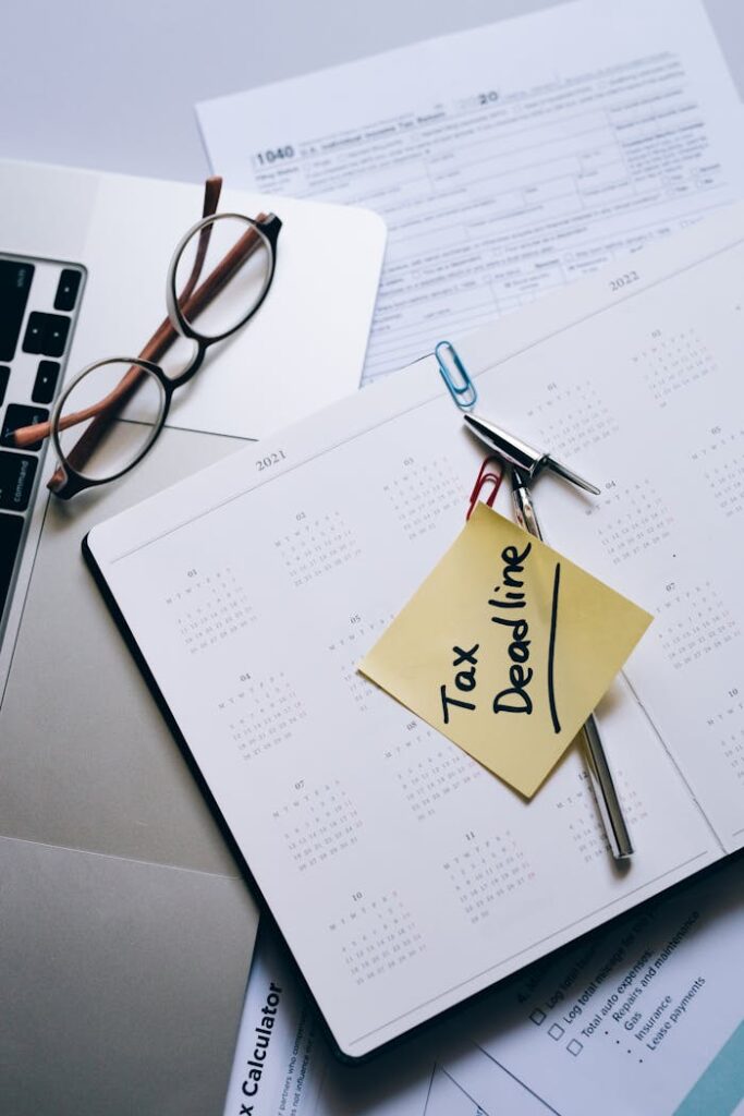pexels photo 8962466 Calendar with tax deadline sticky note on desk with documents, glasses, and laptop.